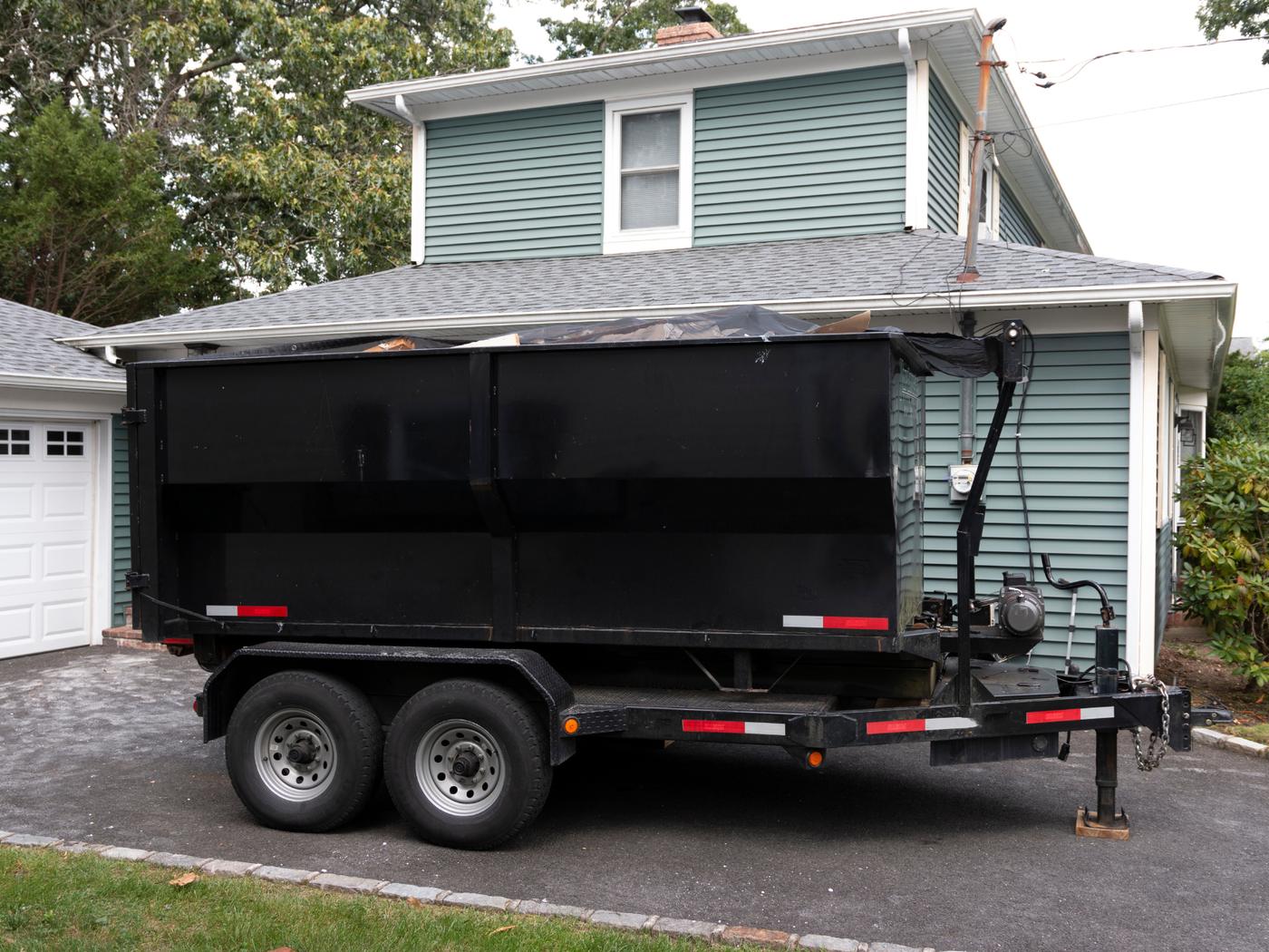 Dump trailer parked in a residential driveway for a household junk pickup